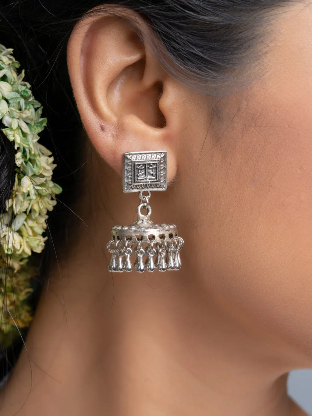 Oxidised silver jhumka earrings with intricate design worn on ear by model
