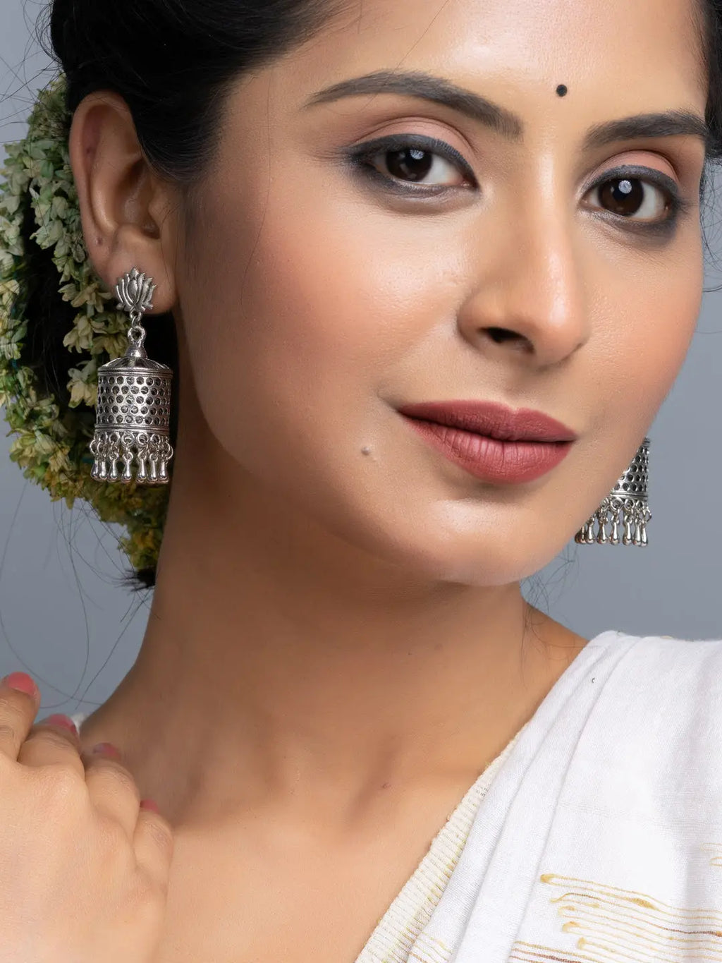 Close-up of woman wearing oxidised silver jhumka earrings with intricate design and traditional attire
