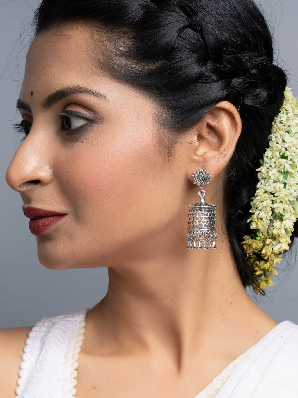 Oxidised silver jhumka earrings worn by woman with braided hair and floral adornment