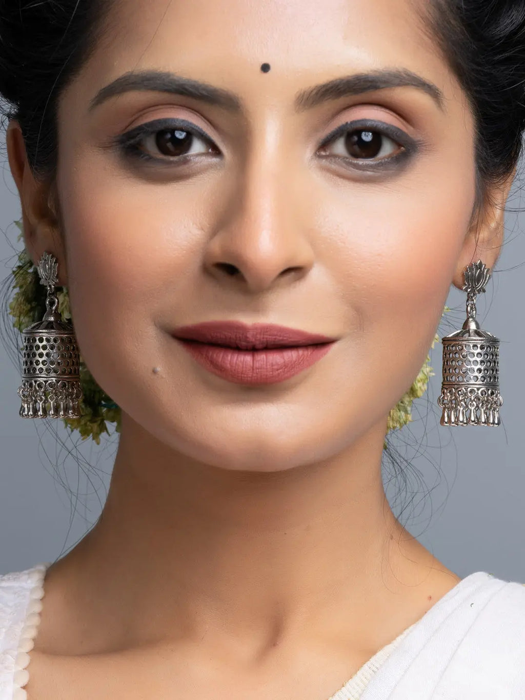 Close-up of woman wearing oxidised silver jhumka earrings with intricate design by LOOK AND ADORN