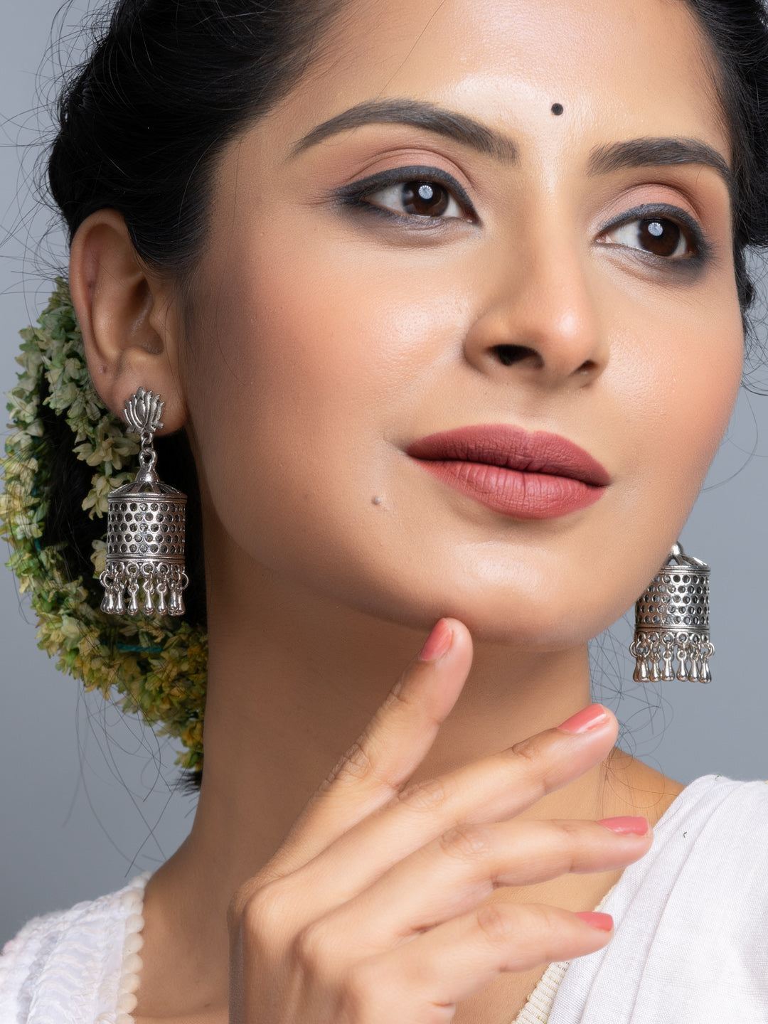 Oxidised silver jhumka earrings worn by woman with traditional hairstyle and makeup