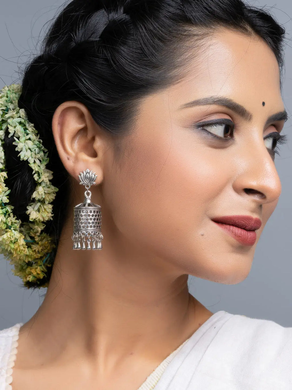 Oxidised silver jhumka earrings worn by woman with braided hair and floral accessories