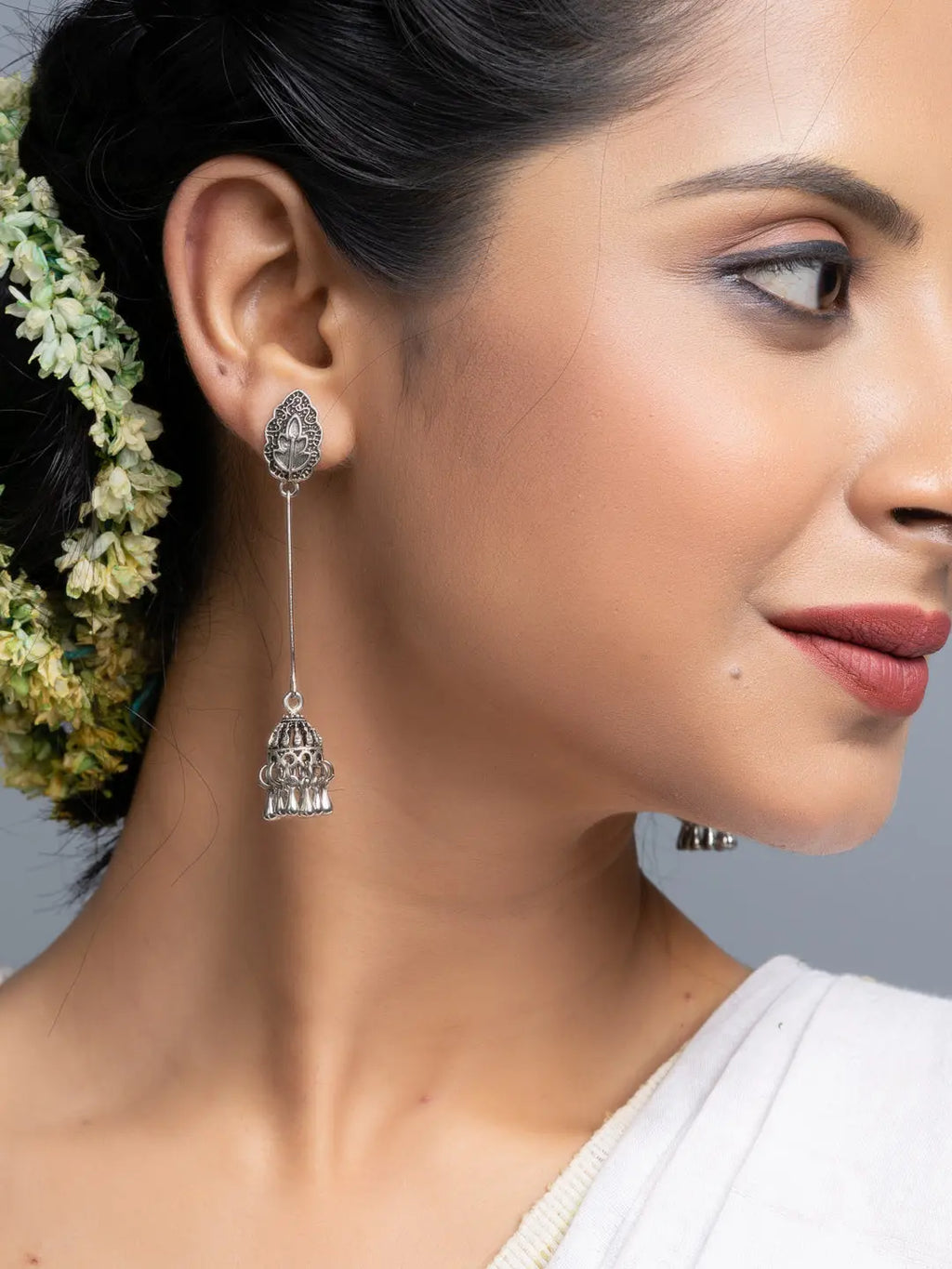 Oxidised silver jhumka earrings worn by woman with floral hair accessory and traditional attire