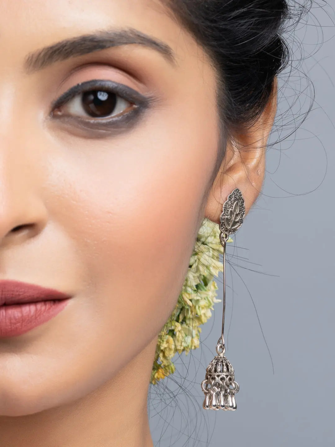 Close-up of a woman wearing oxidised silver jhumka earrings with intricate detailing