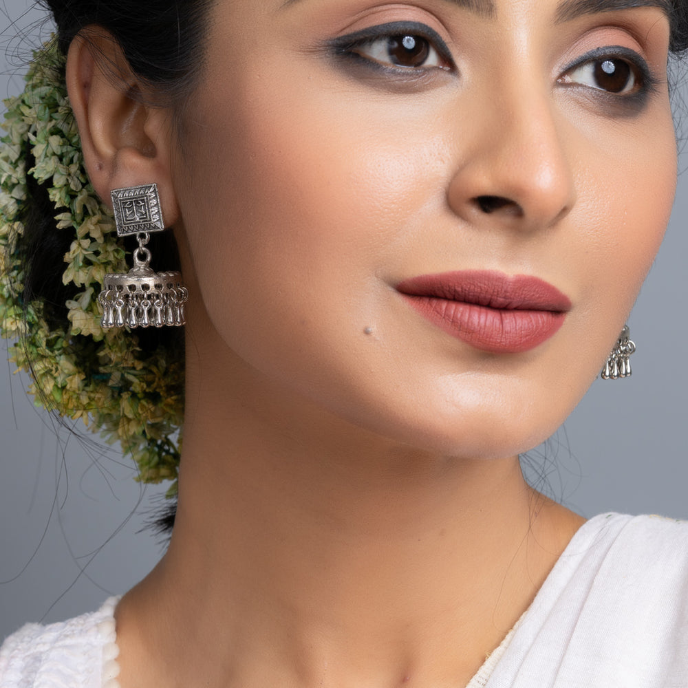 Oxidised silver jhumka earrings worn by woman with traditional floral hair accessory