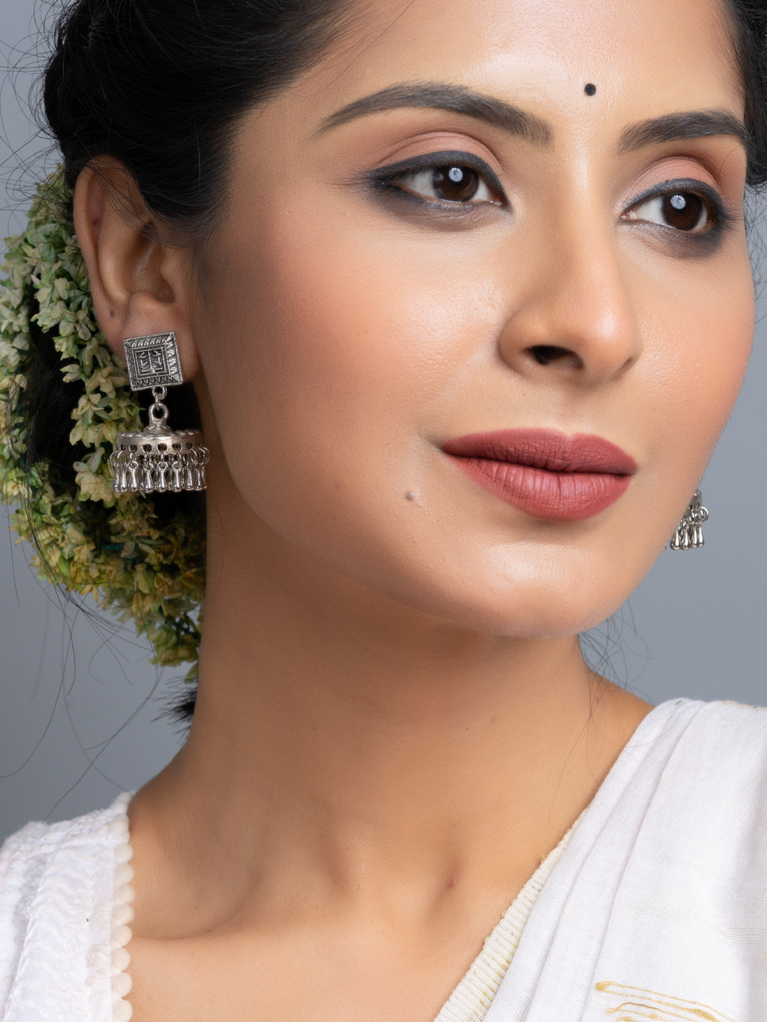 Oxidised silver jhumka earrings worn by woman with traditional floral hair accessory