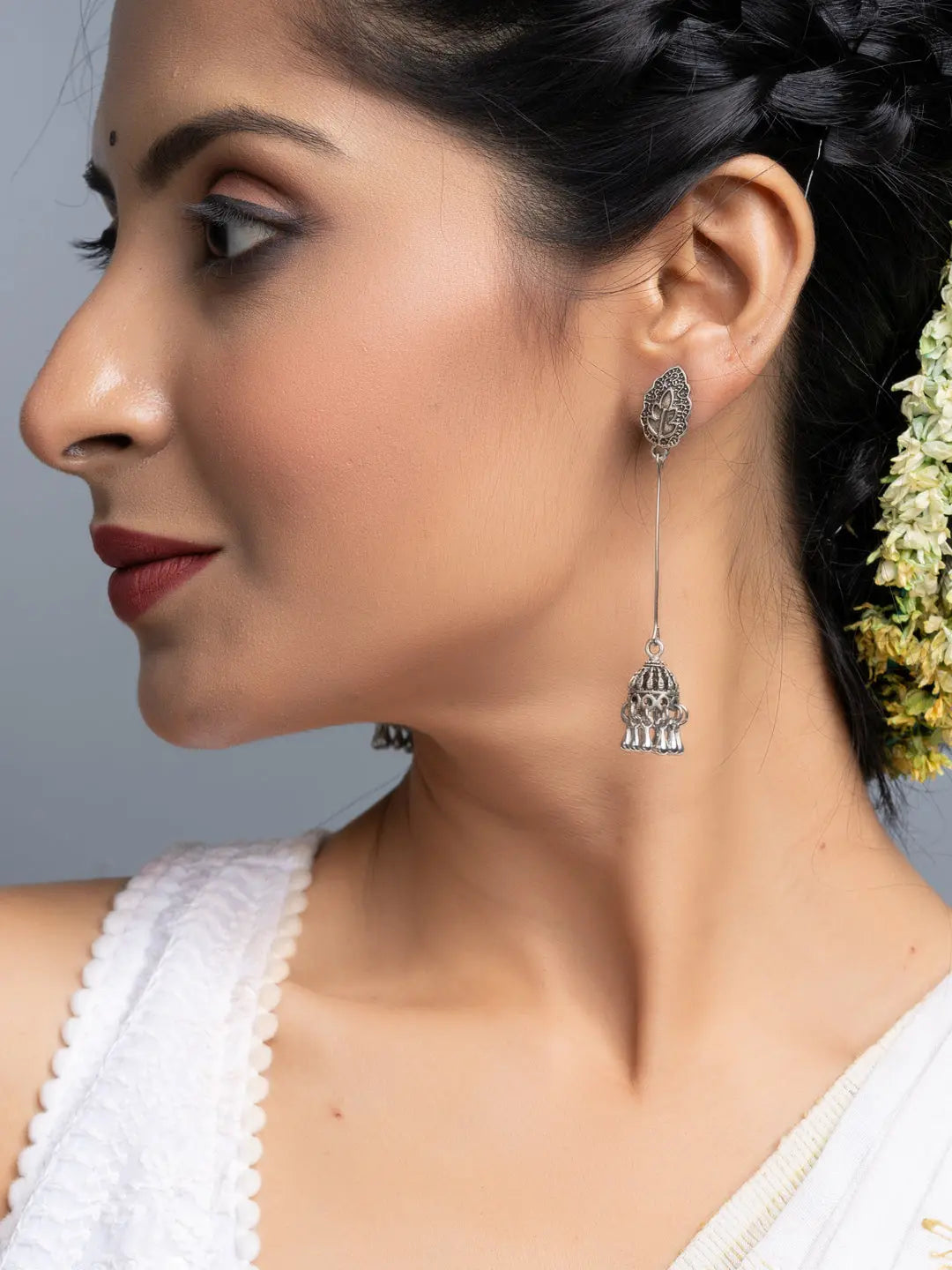 Oxidised silver jhumka earrings worn by woman with traditional braided hairstyle and white outfit