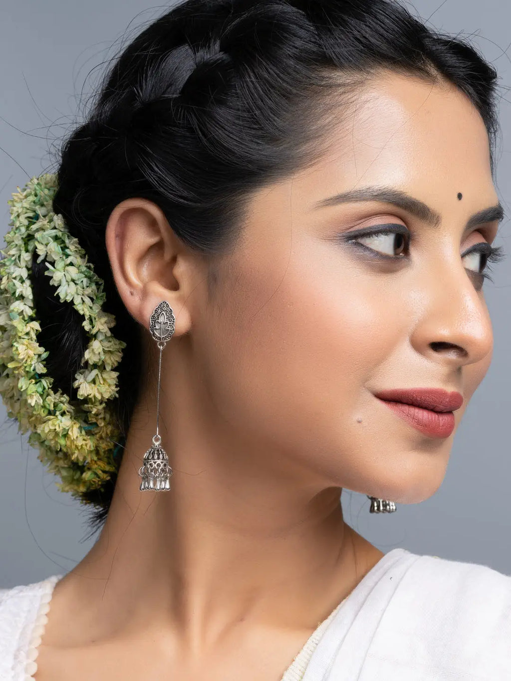 Oxidised silver jhumka earrings worn by woman with braided hair and floral accessories