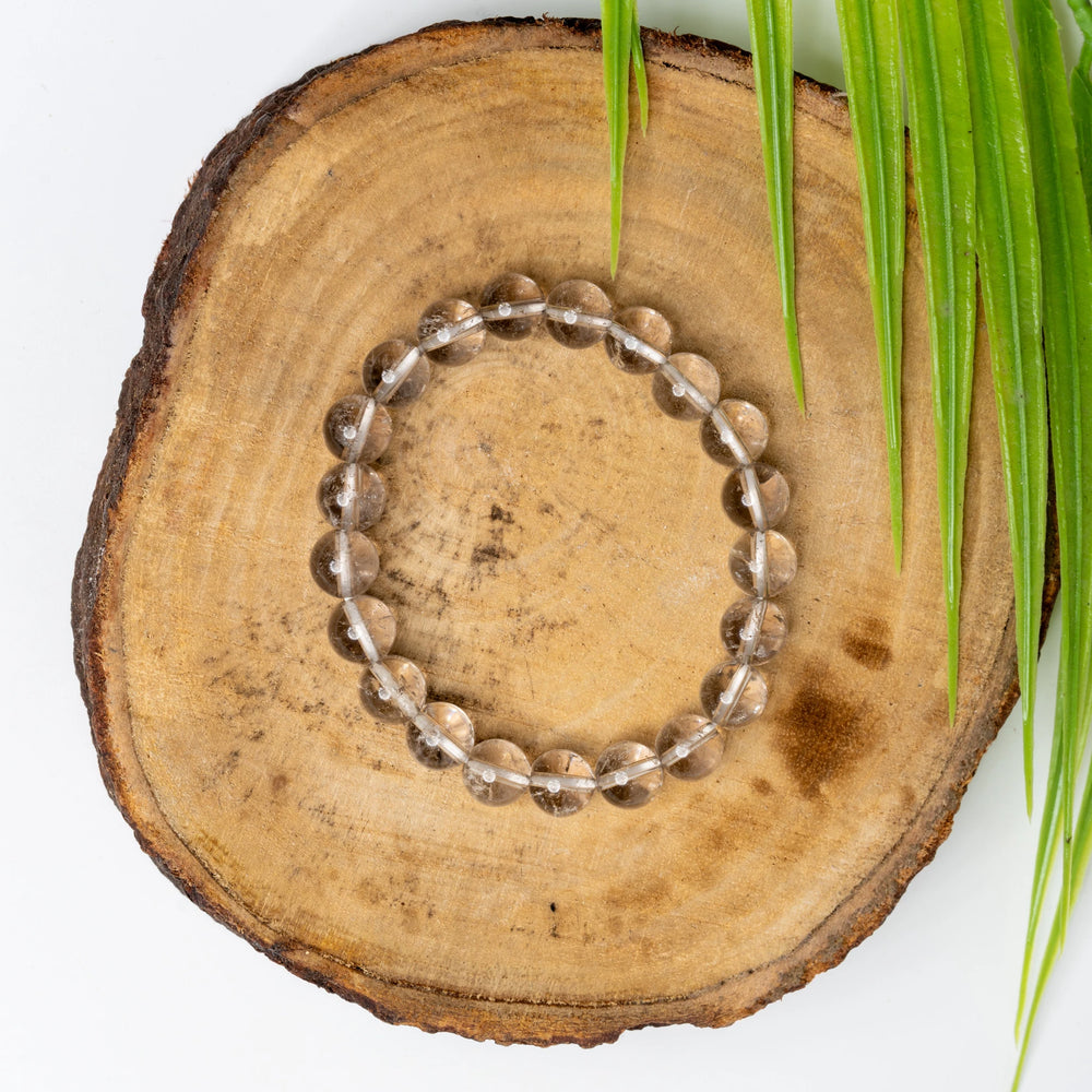 Smokey quartz bracelet on a wooden surface with greenery for a natural touch