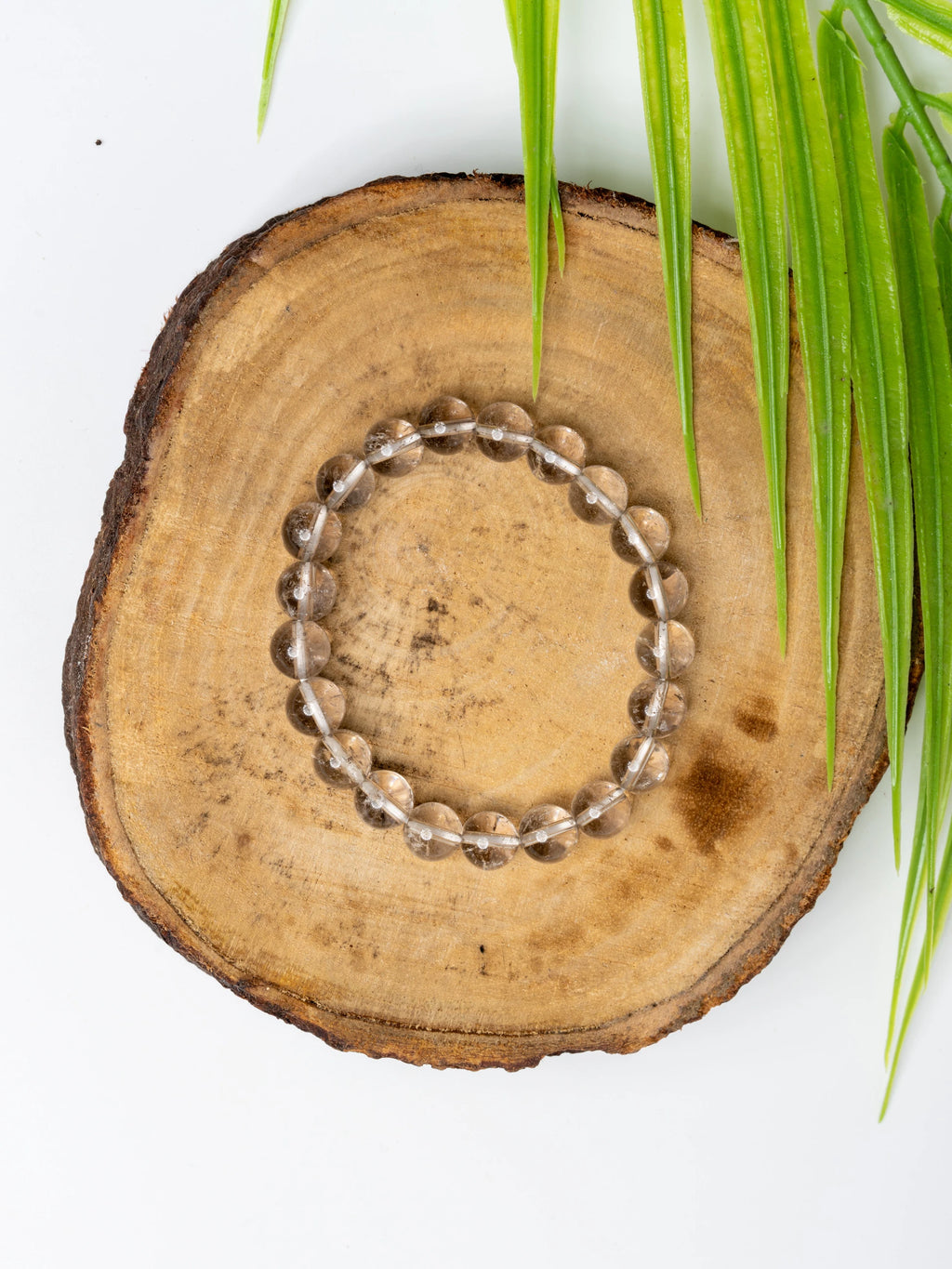 Smokey quartz bracelet on a wooden surface with greenery for a natural touch