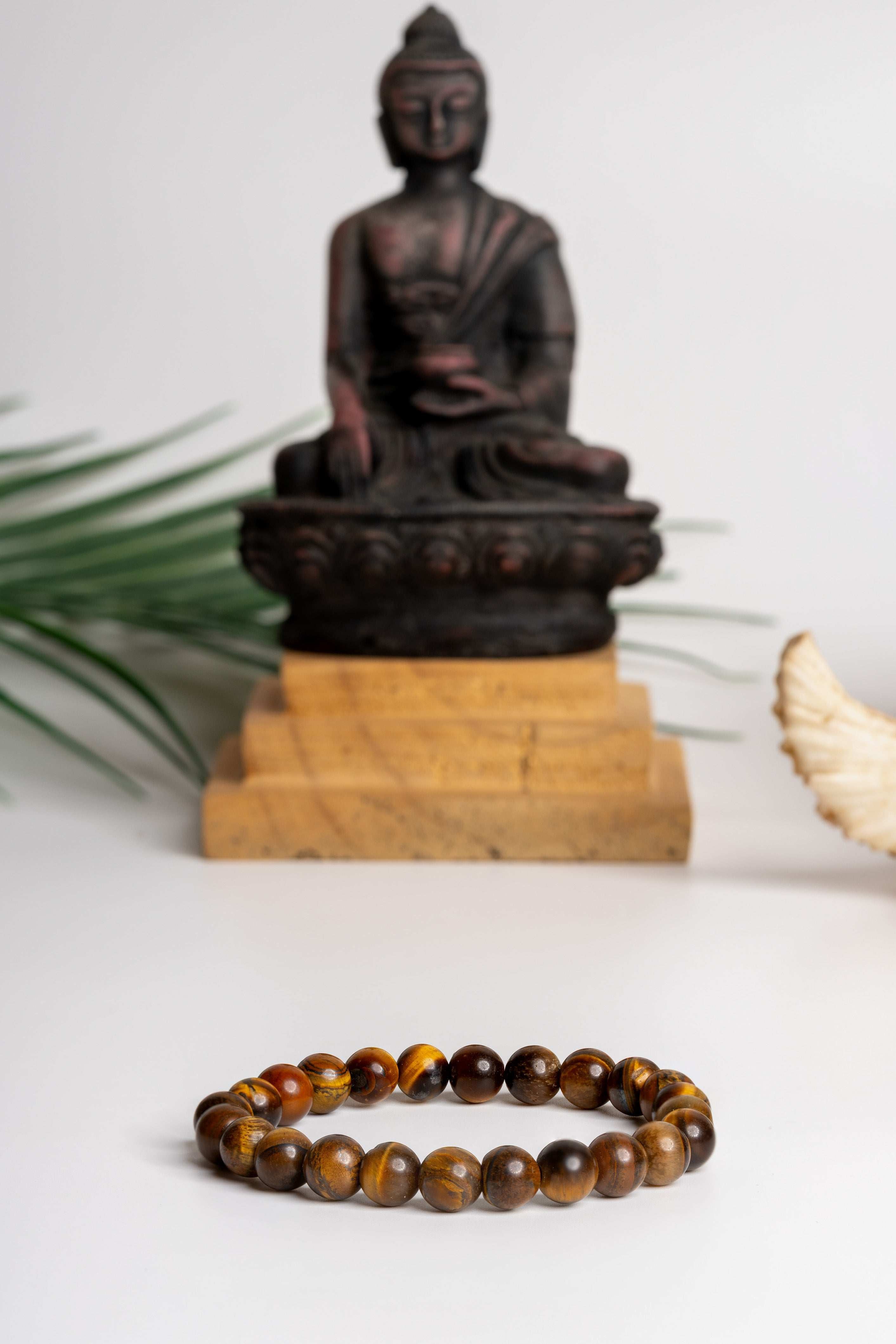Tiger eye bracelet with polished stones, set against a serene Buddha statue background