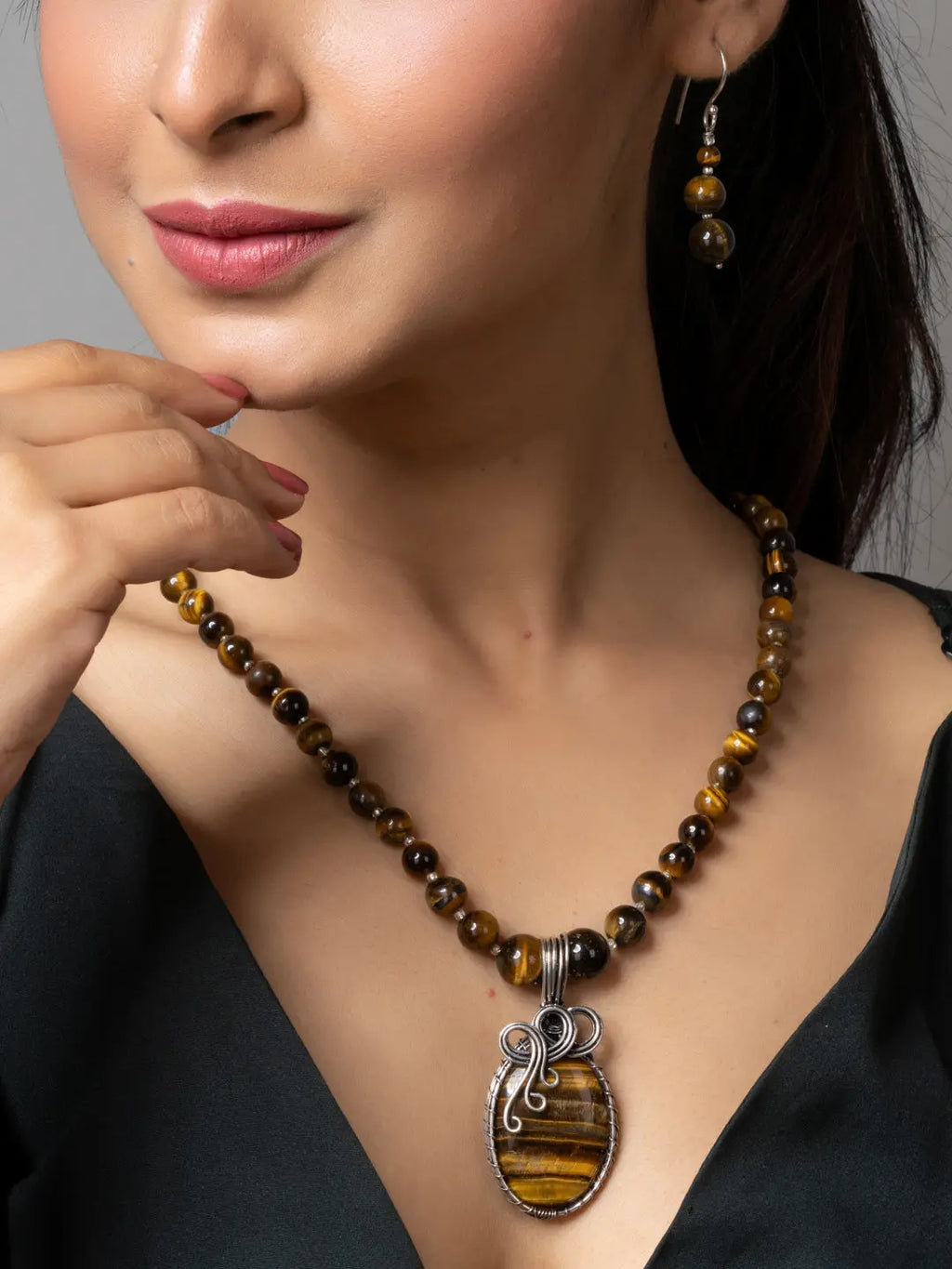 Handmade tiger eye necklace with polished beads and silver pendant worn by woman with matching earrings