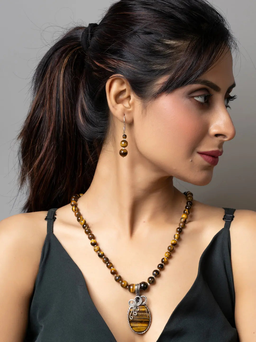 Handmade tiger eye necklace and matching earrings worn by woman with black top for elegant style