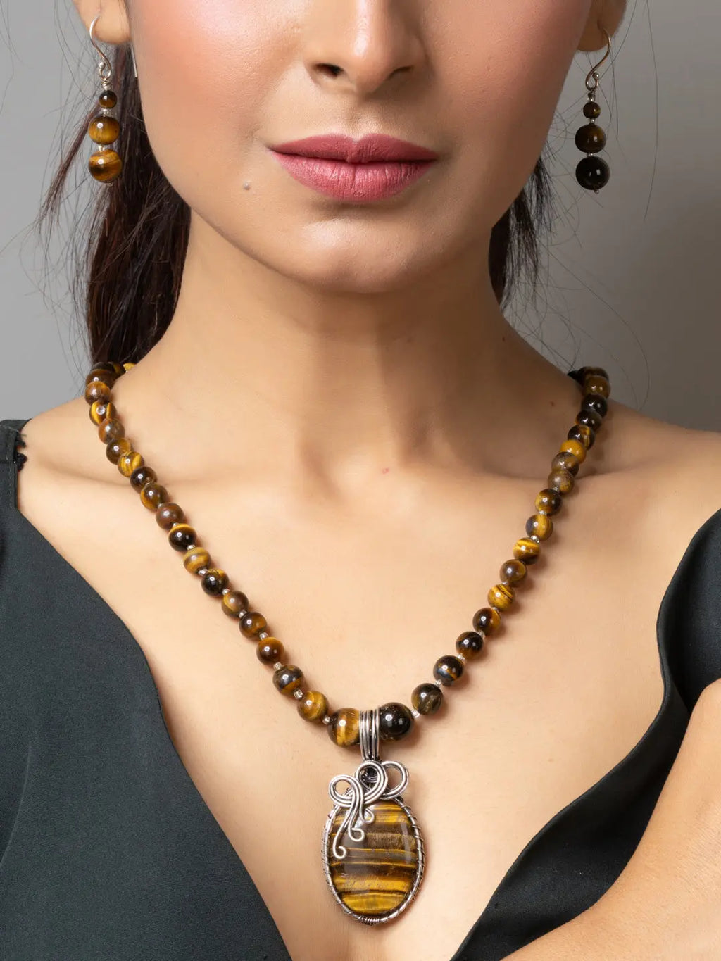 Handmade tiger eye necklace with polished beads and a wire-wrapped tiger eye pendant worn with matching earrings