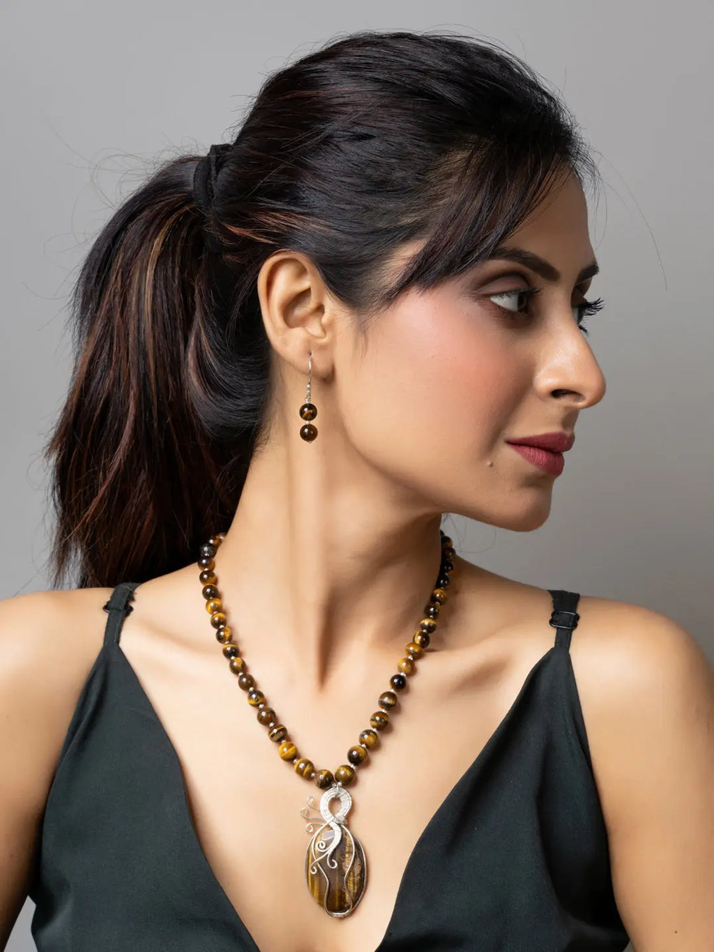 Woman wearing handmade tiger eye necklace with matching earrings and black top by LOOK AND ADORN