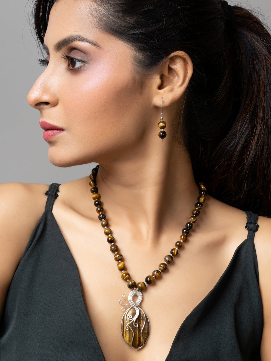 Woman wearing handmade tiger eye necklace with matching earrings and pendant by LOOK AND ADORN