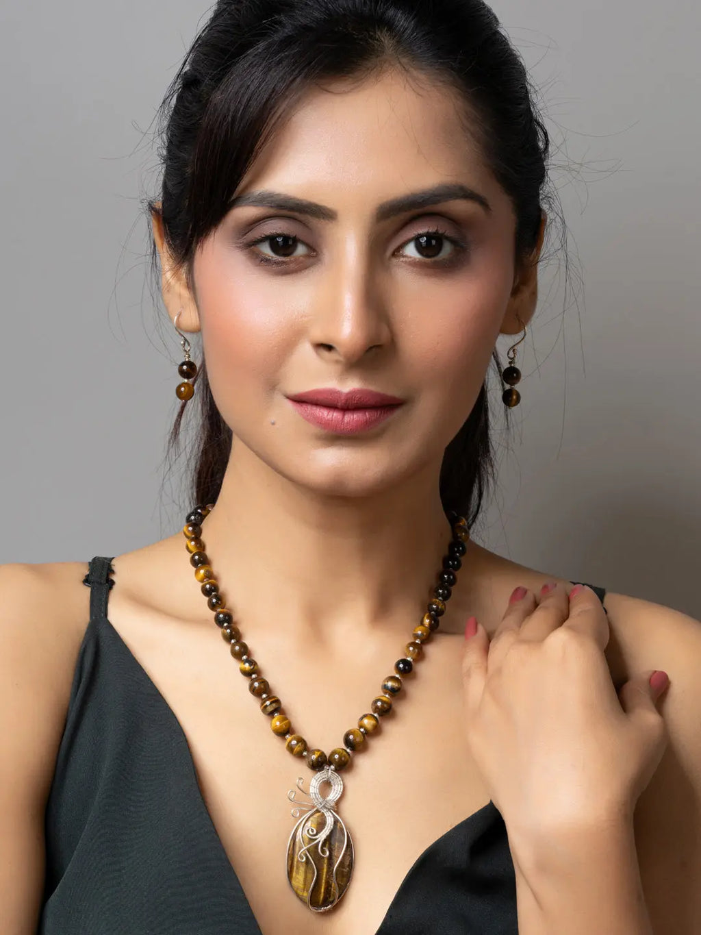 Handmade tiger eye necklace with pendant worn by woman, featuring matching tiger eye earrings
