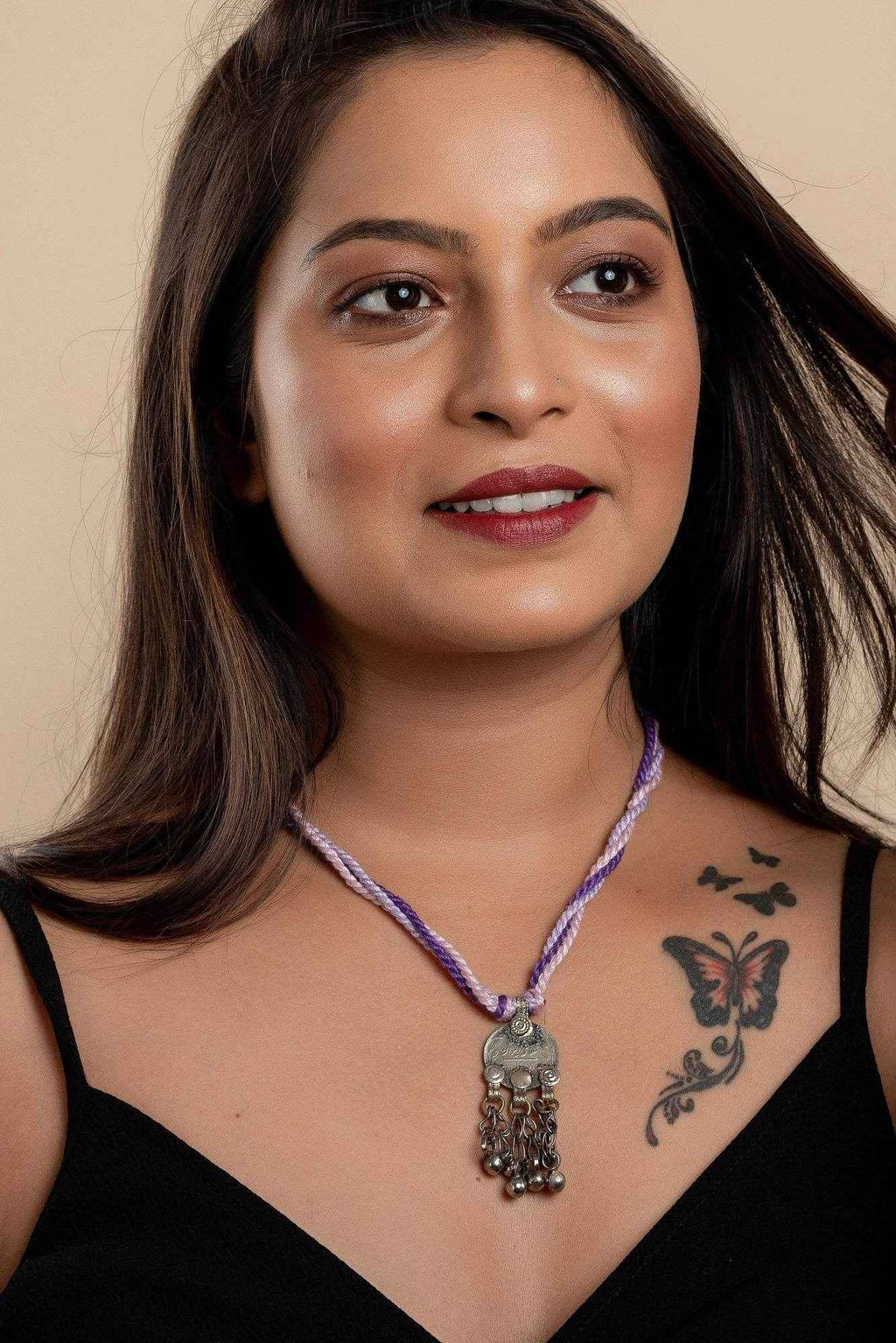 Woman wearing a purple braided Afghani Necklace with silver and dangling charms from LOOK AND ADORN