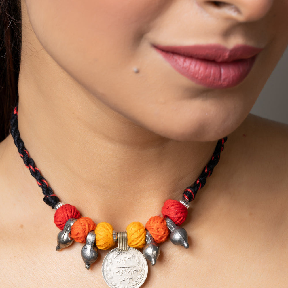 Close-up of a woman wearing a colorful handmade afghani pendant necklace with metal and thread beads