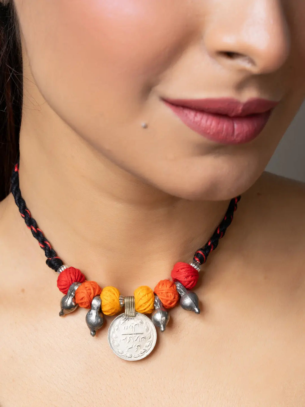 Close-up of a woman wearing a colorful handmade afghani pendant necklace with metal and thread beads