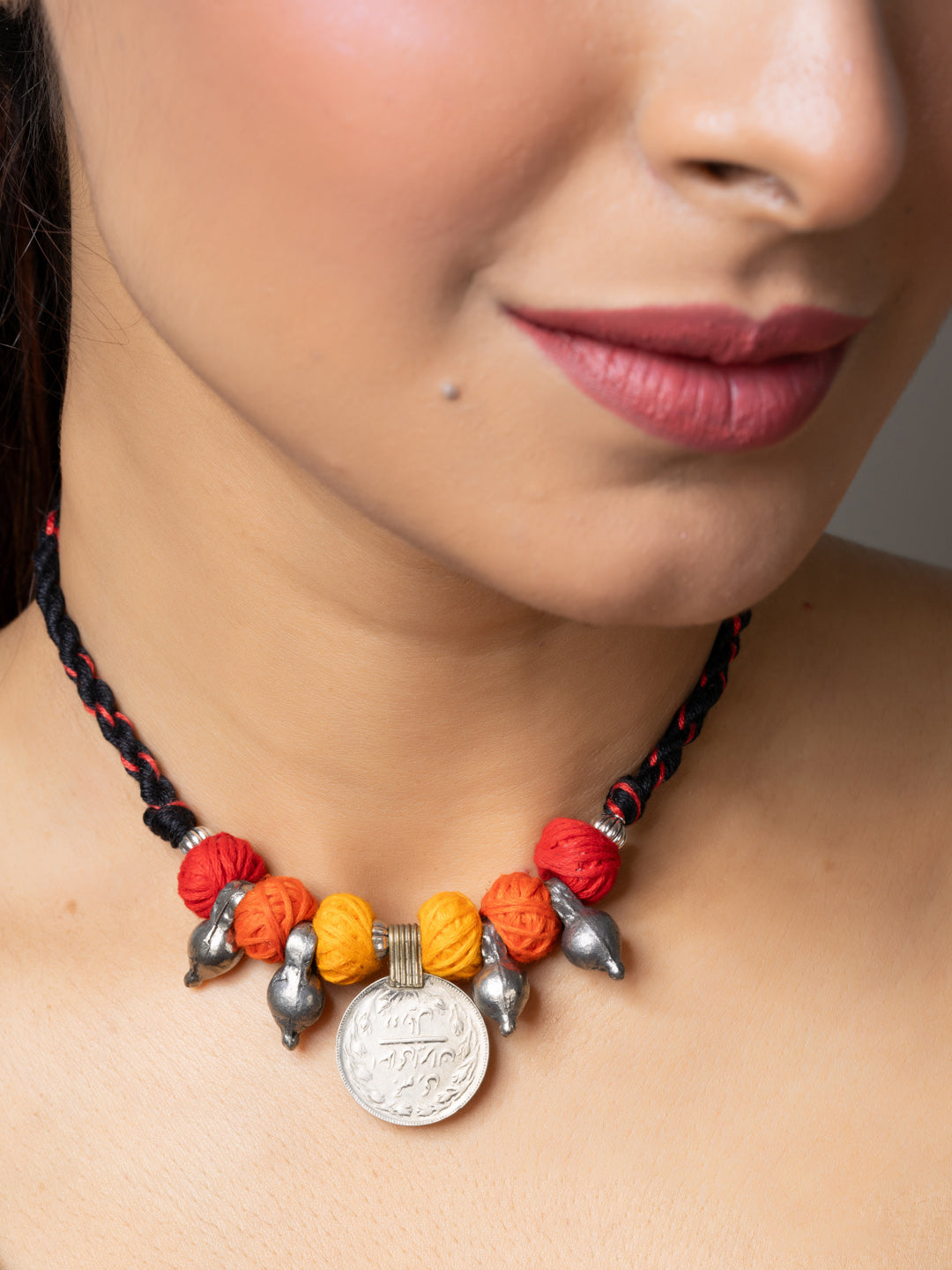 Close-up of a woman wearing a colorful handmade afghani pendant necklace with metal and thread beads