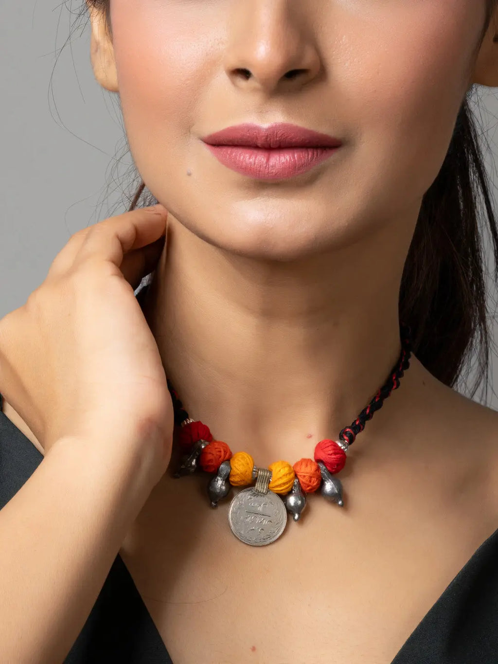 Afghani pendant necklace with red and orange beads and coin charm worn by woman