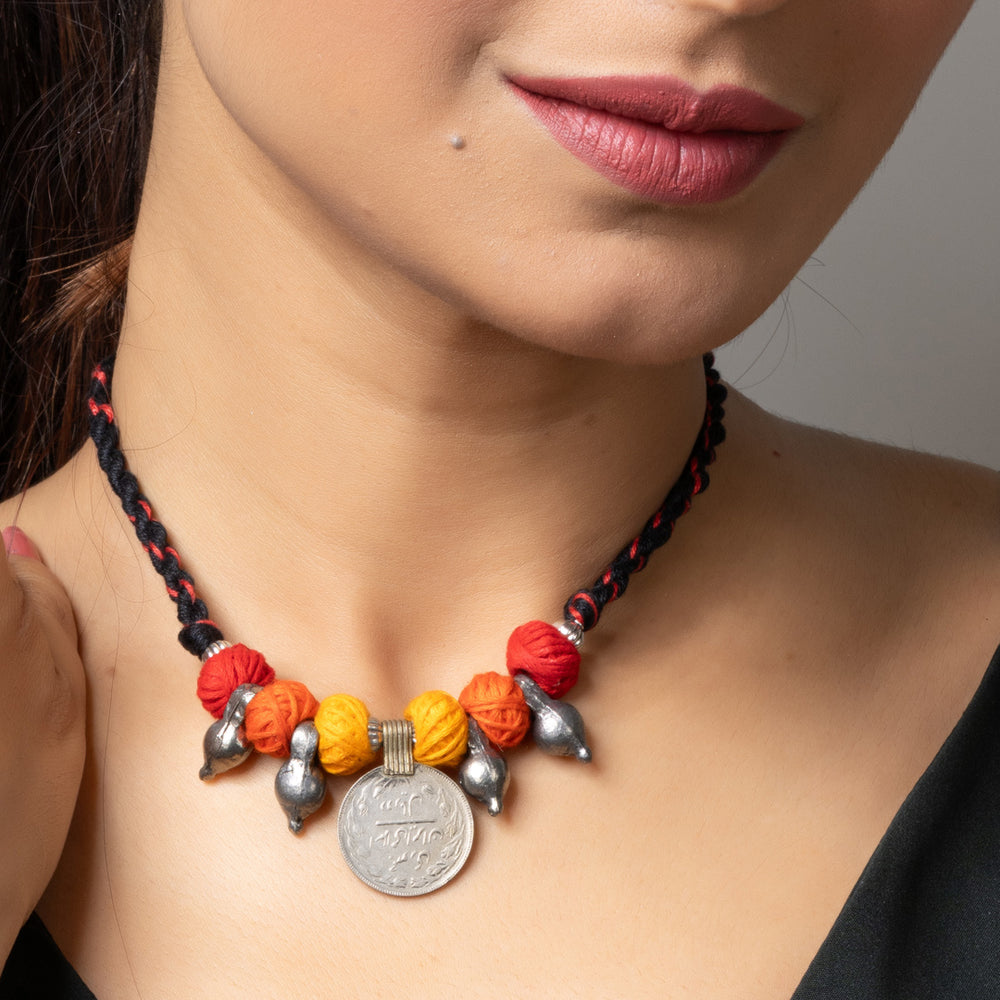 Afghani pendant necklace with colorful beads and silver coin charm worn by woman