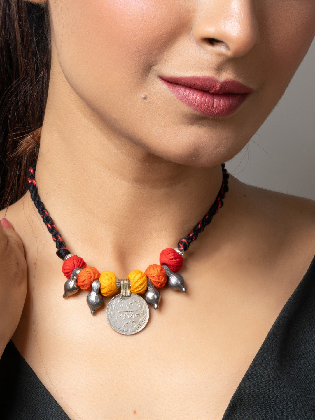 Afghani pendant necklace with colorful beads and silver coin charm worn by woman