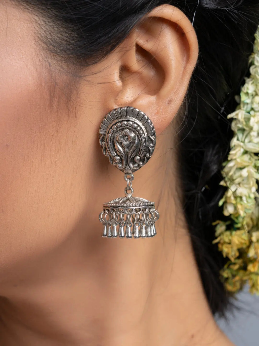 Oxidised silver jhumka earrings with intricate detailing worn on ear by model