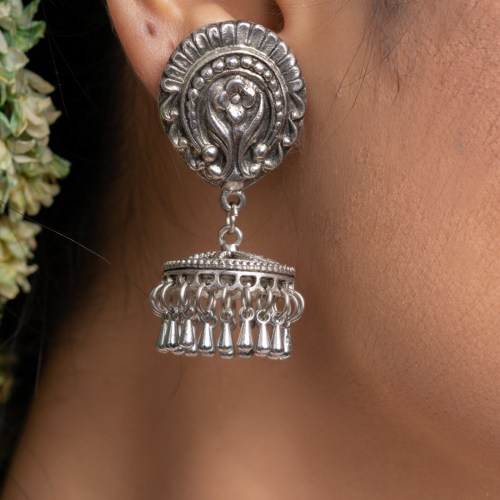 Oxidised silver jhumka earrings with intricate detailing worn on ear for traditional style