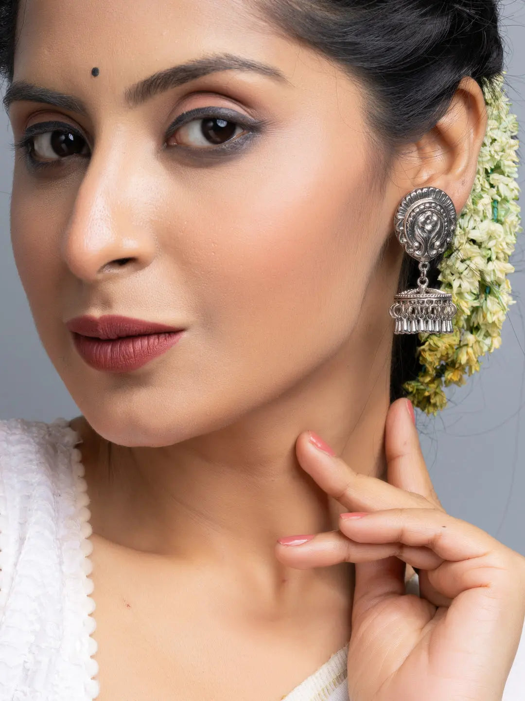 Close-up of woman wearing oxidised silver jhumka earrings with intricate traditional design