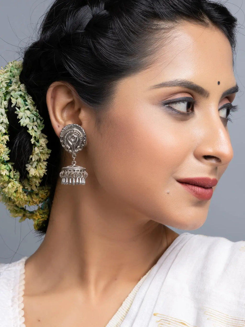 Oxidised silver jhumka earrings worn by woman with braided hair and traditional attire