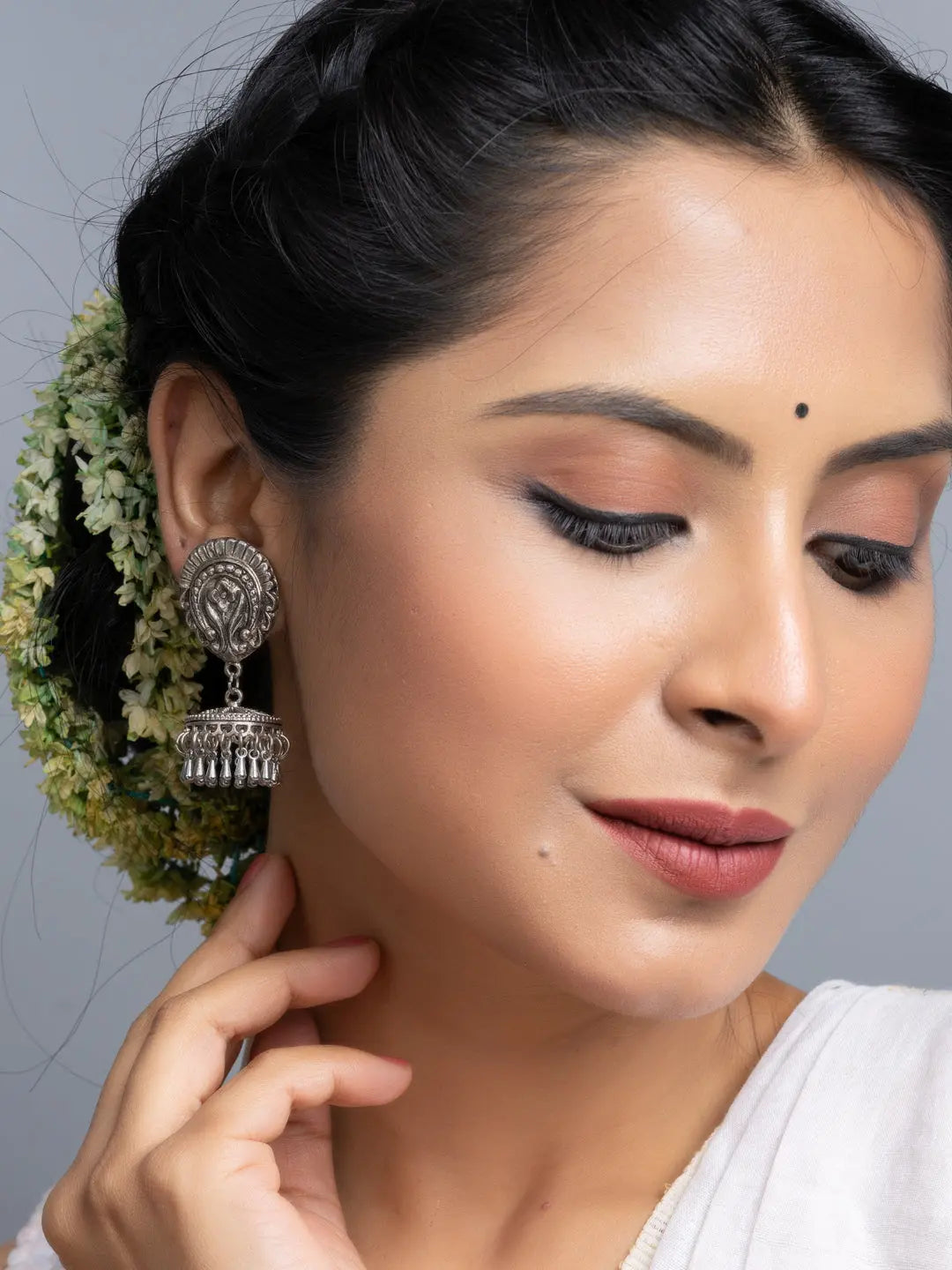 Close-up of oxidised silver jhumka earrings worn by woman with traditional hairstyle and makeup