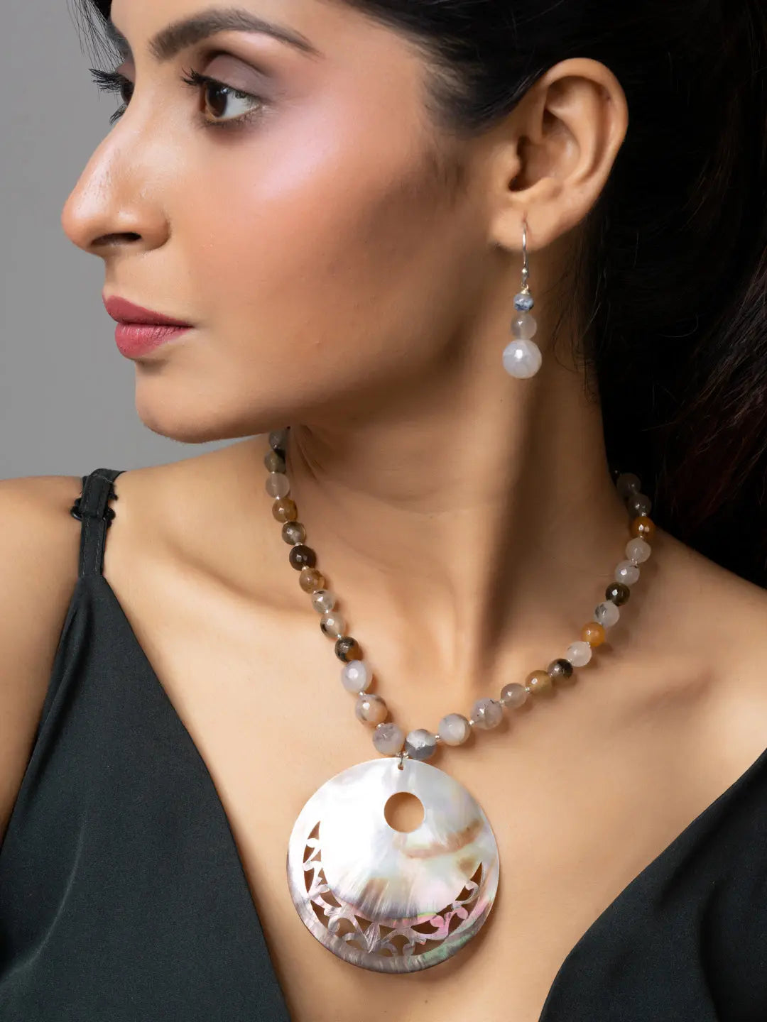 Woman wearing handmade jewelry with a Mother of Pearl Pendant necklace and matching earrings