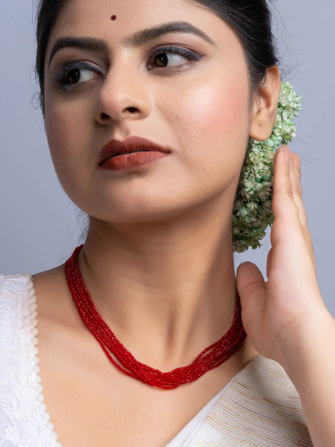 Handmade red crystal necklace worn by woman with traditional attire and floral hair accessory